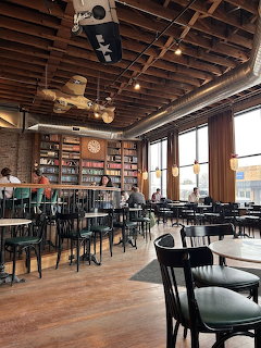 Cozy coffee shop interior with wooden ceiling, tables, chairs, and bookshelves