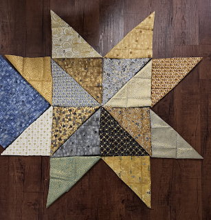 Eight-pointed star quilt block with gold, blue and cream Klimt-pattern fabrics on wood surface