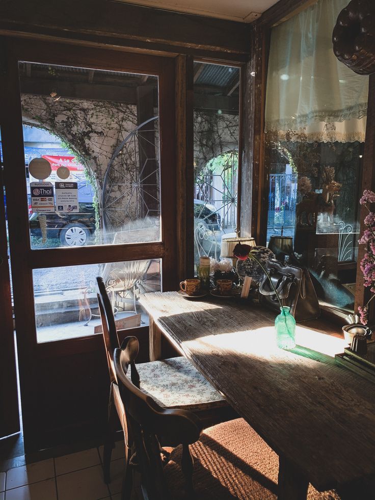 Sunlit cafe interior with wooden furniture and large windows overlooking street