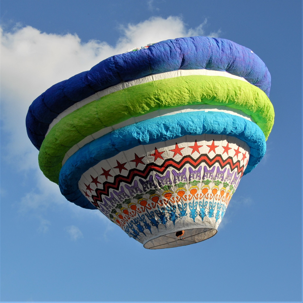 Colorful hot air balloon with blue, green and patterned envelope against blue sky