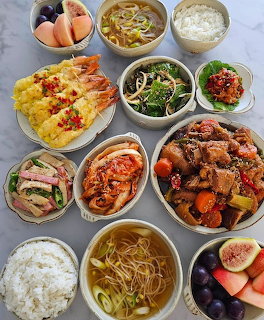 Overhead view of Korean meal spread with braised meat, kimchi, rice, shrimp, noodle soup and side dishes