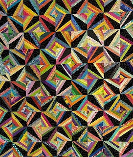Colorful quilt with geometric diamond pattern in rainbow fabrics on black background