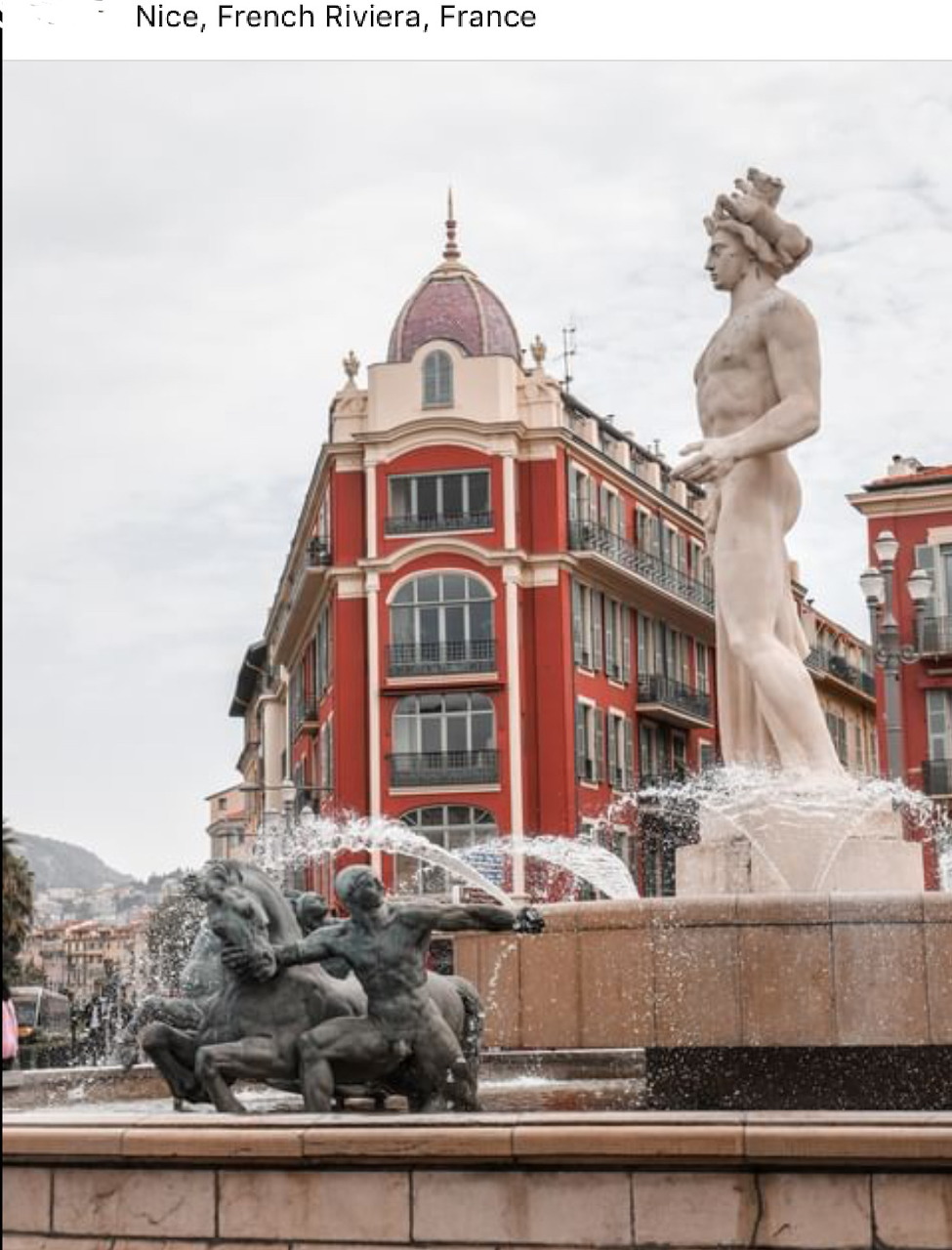 Classical fountain statue with red historic building in Nice, France