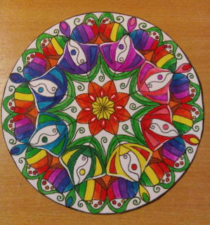 Colorful mandala with symmetrical rainbow patterns and central star on wood surface