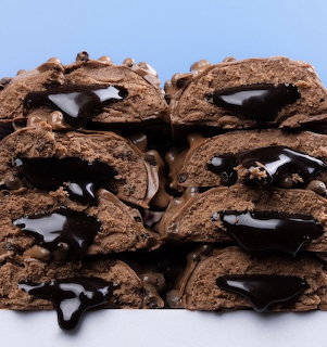 Stack of chocolate cookies with dark chocolate drizzle on a blue background