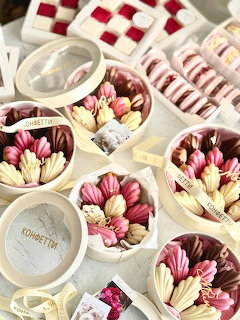 Round gift boxes filled with flower-shaped decorated sweets in pink, cream, and burgundy colors