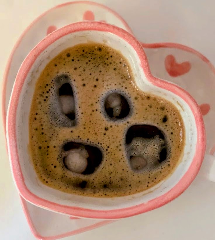 Overhead view of coffee with foam in a pink heart-shaped mug