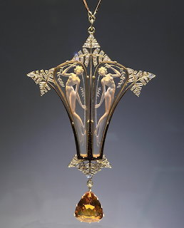 Art Nouveau gold pendant with ornate floral design and amber citrine drop stone on dark background