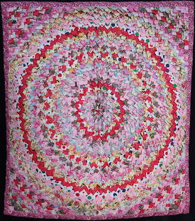 Patchwork quilt with concentric spiral pattern in pink and floral fabrics