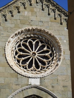 Circular rose window with decorative stone tracery on a light stone church facade