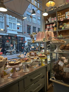 Amsterdam cafe interior showing pastry display counter with cakes and baked goods, street view through window