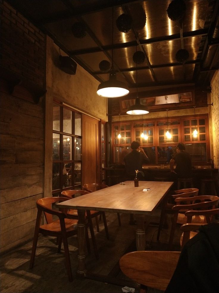 Warm coffee shop interior with wooden walls, pendant lights, and dining table at evening