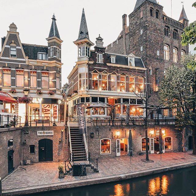 Historic canal buildings lit at dusk beside a calm waterway in Utrecht