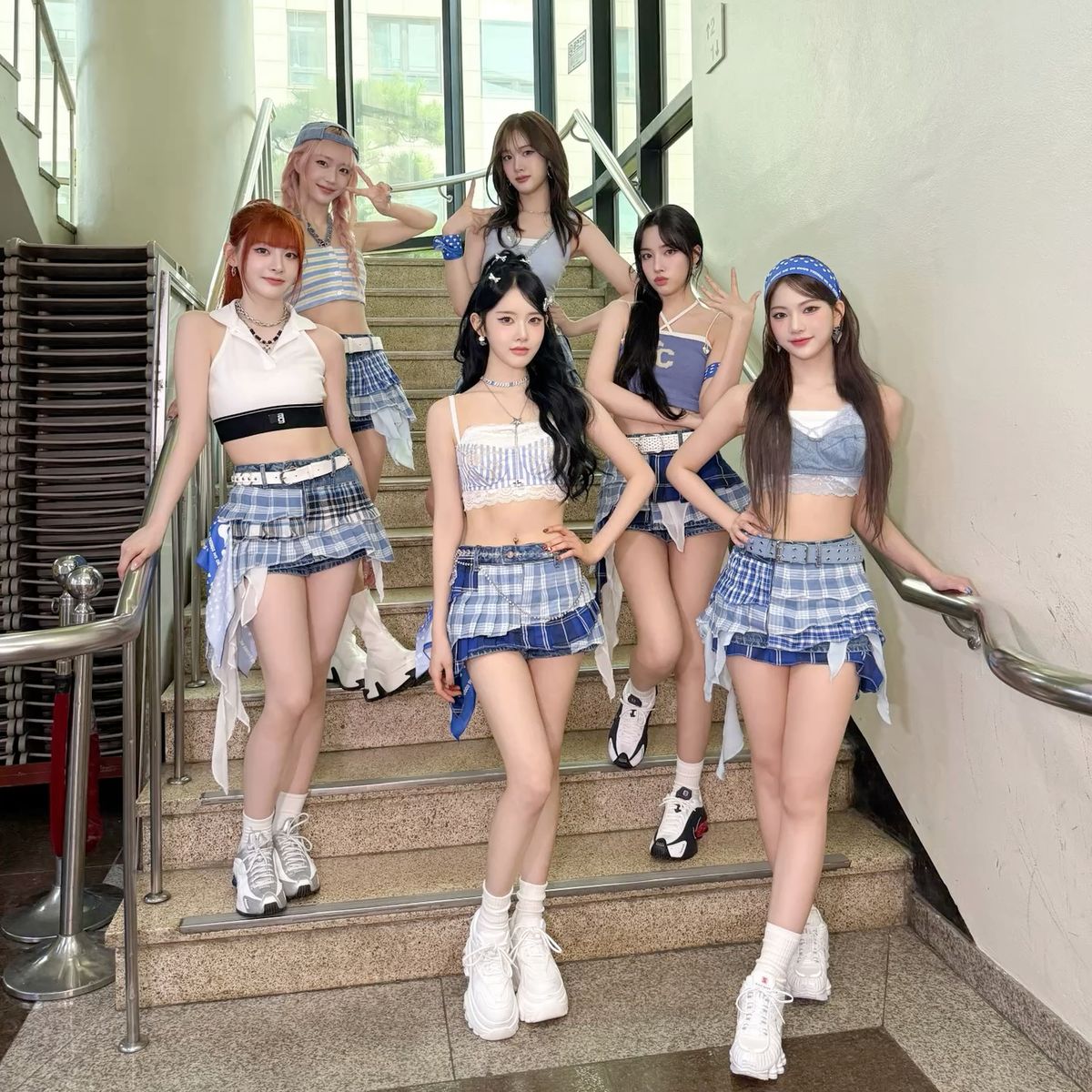 Six women in matching outfits posing together on indoor stairs