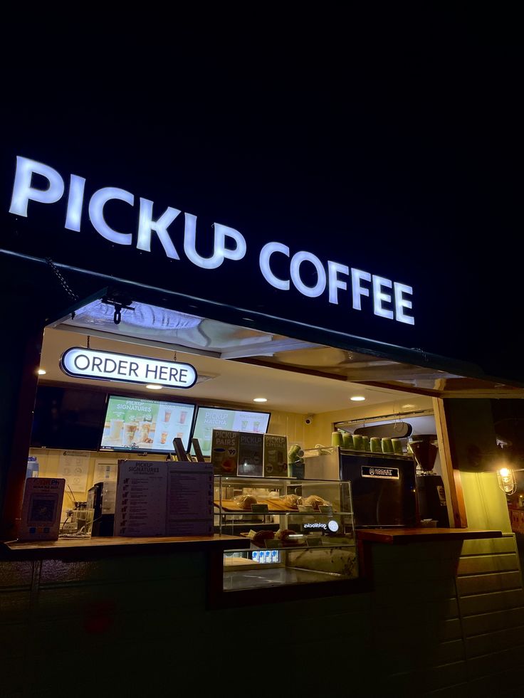 Pickup Coffee shop exterior at night with illuminated signage and order counter