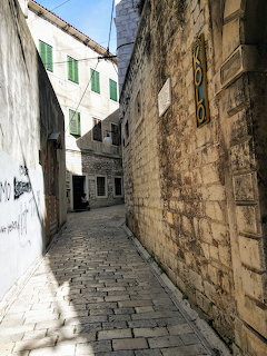 Narrow cobblestone alley between old stone buildings in Šibenik, Croatia