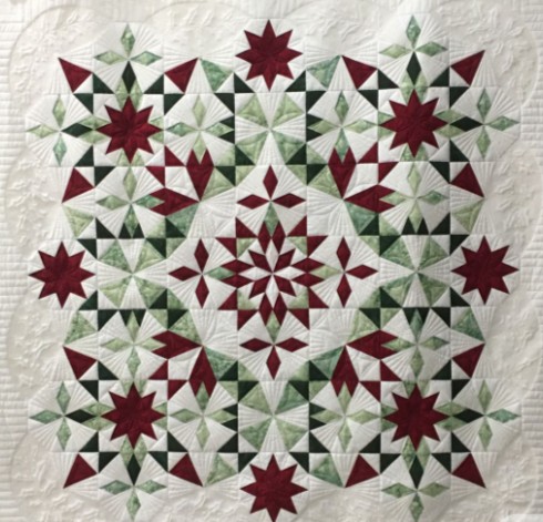 Patchwork quilt with a large eight-point Christmas star in red, green and cream.