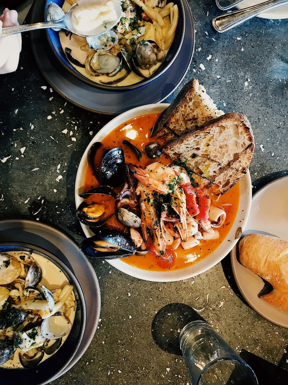 Bowl of Italian seafood soup with mussels, shrimp, and crusty bread on a dark table
