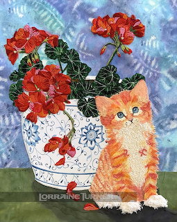 Textile art of an orange tabby kitten next to a blue and white vase with red geranium flowers