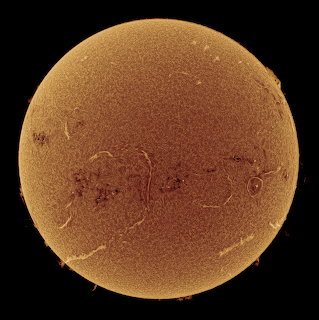 Detailed photograph of the sun's orange surface with visible sunspots and solar texture against black space