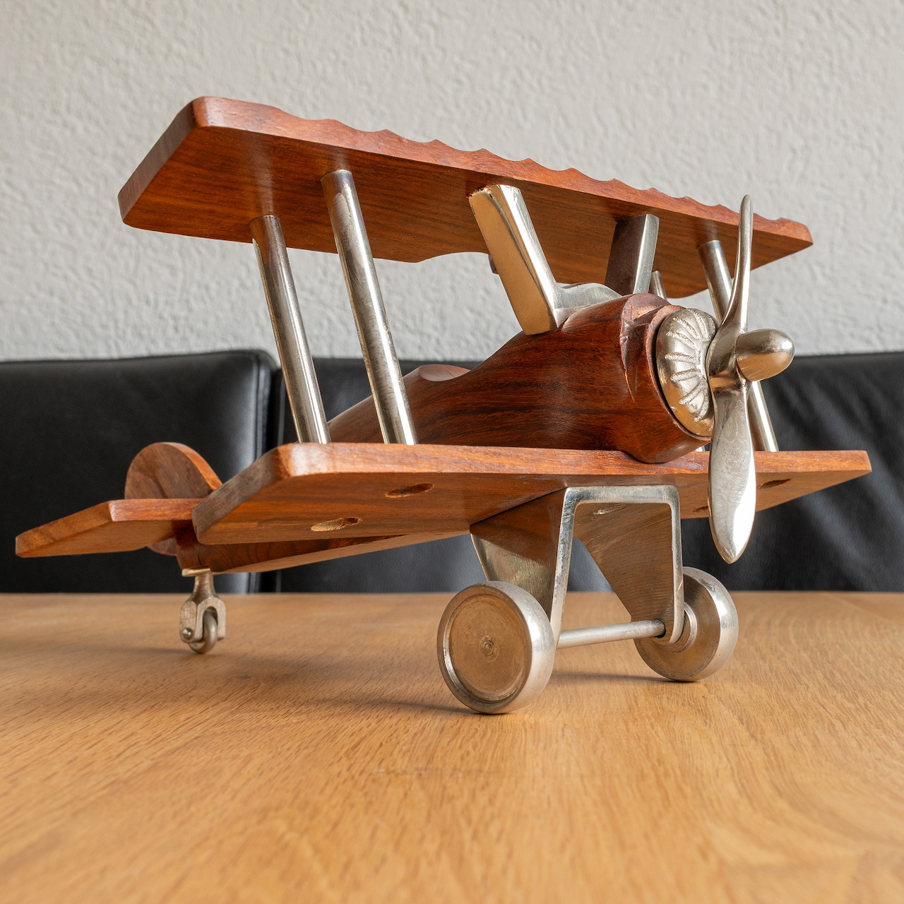 Wooden toy biplane model with double wings and metal propeller on wooden table