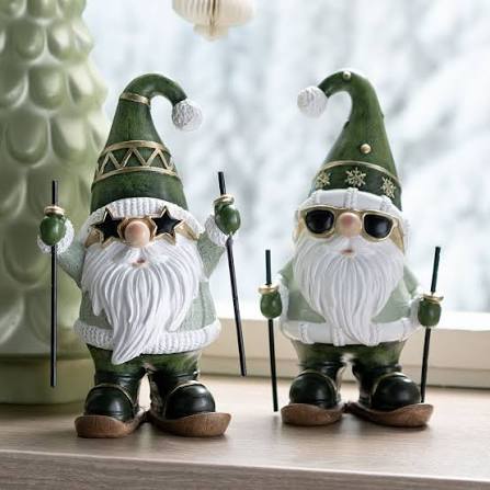 Two festive gnome figurines with green hats and white beards holding ski poles