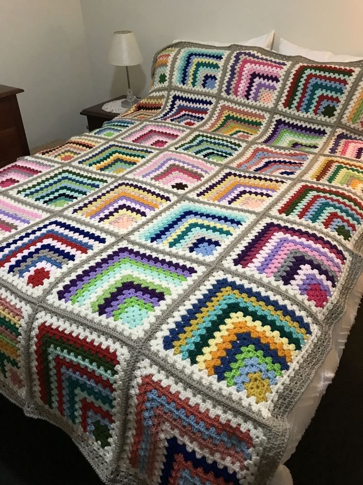 Colorful crochet granny square blanket with rainbow pattern on bed
