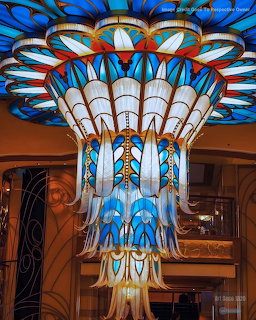 Elaborate art deco chandelier with blue and white geometric tiers and gold accents hanging in a room