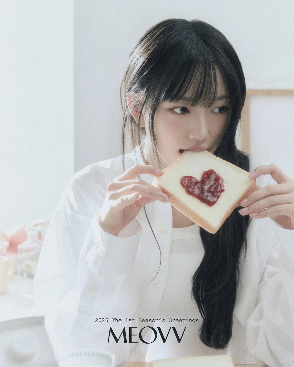 Young woman with long black hair holding a slice of toast with jam indoors