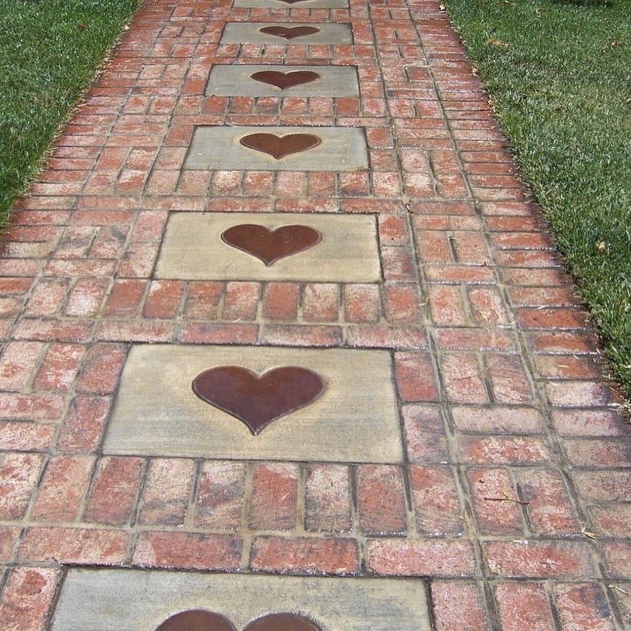 Brick pathway with heart-shaped stones embedded in decorative pattern along garden walk