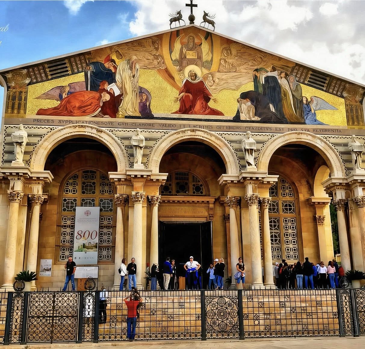 Historic church facade with arches, columns, and a golden religious mosaic above the entrance