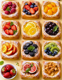 Grid of twelve square fruit tarts with various fresh fruit toppings and powdered sugar on golden pastry