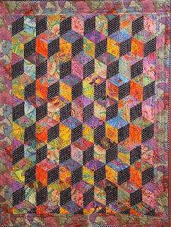 Patchwork quilt with 3D tumbling blocks pattern in orange, pink, yellow, and black fabrics