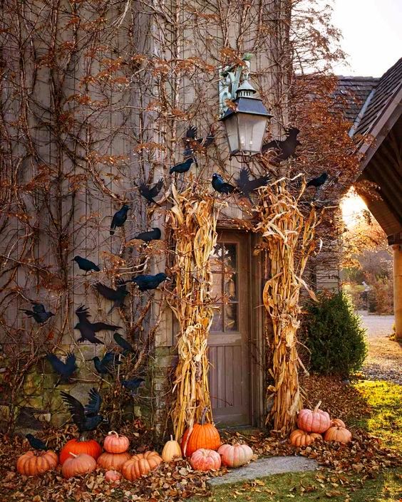 Autumn doorway with cornstalks, black crows, and pumpkins around the entrance