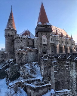 Medieval Gothic castle with towers and snow-covered walls under blue sky