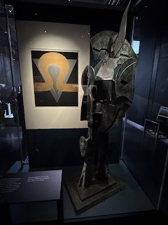 Abstract sculpture and framed artwork displayed in a dark museum case