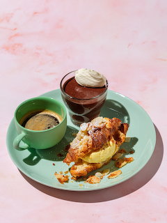 Espresso cup, chocolate dessert with cream, and caramel-drizzled pastry on turquoise plate