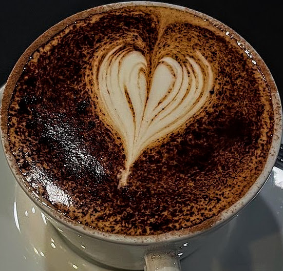 Coffee cup with heart latte art and cocoa powder on foam