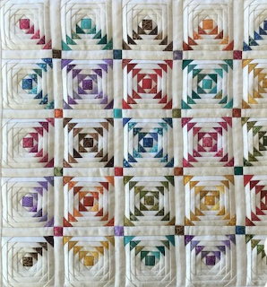 Patchwork quilt with grid of colorful pineapple log cabin blocks on cream fabric