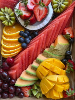 Colorful fruit platter with watermelon, mango, cantaloupe, strawberries, oranges, kiwi, blueberies, and grapes