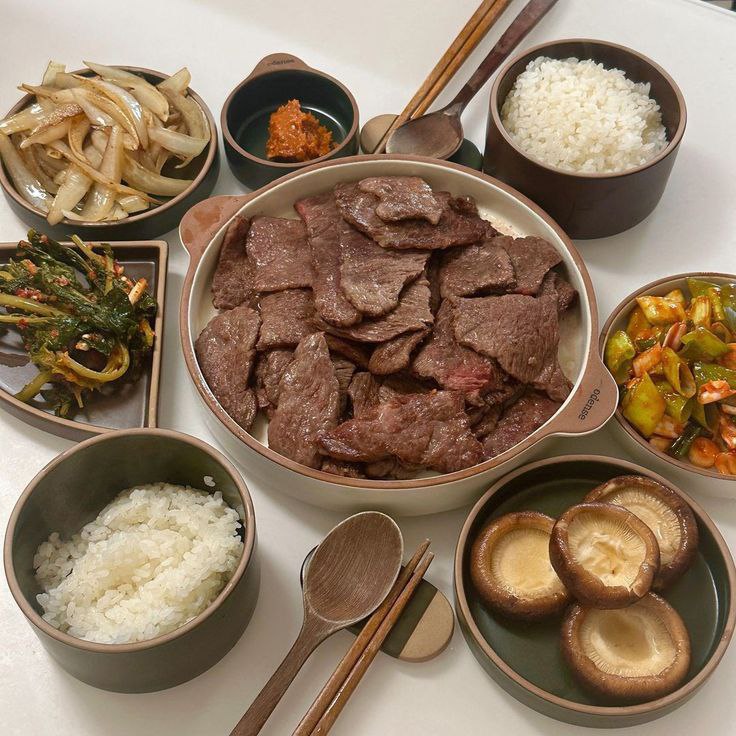 Overhead view of Korean bulgogi meal with rice, side dishes, and mushrooms on a table