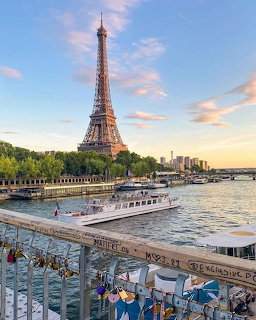 Eiffel Tower viewed from Seine River promenade at sunset with tourists and boat