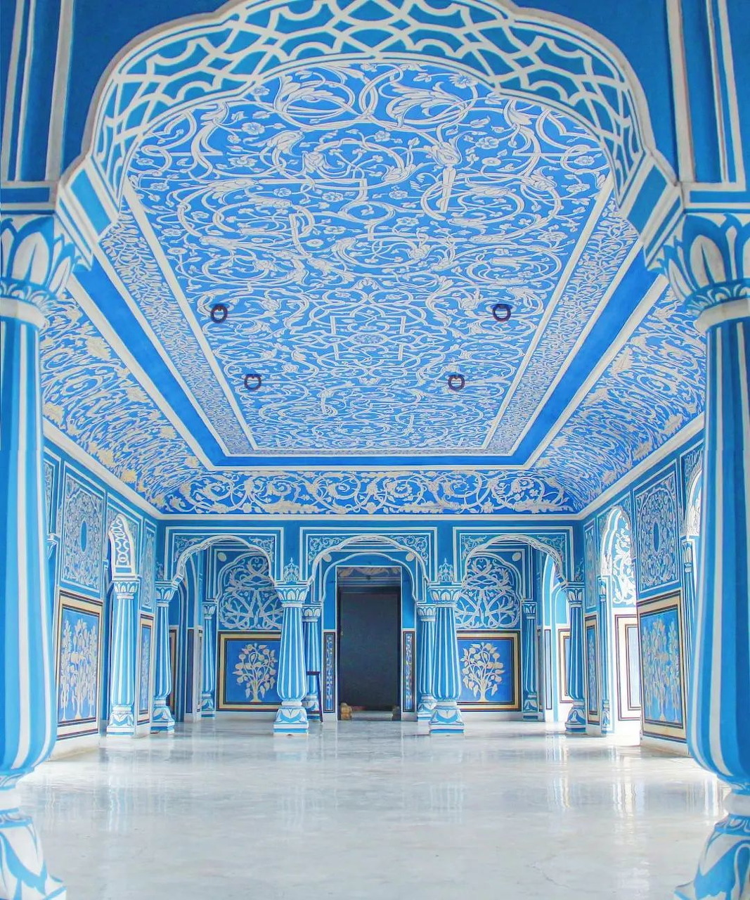 Grand blue and white ornamental hall inside City Palace, Jaipur, with arched columns and detailed ceiling carvings