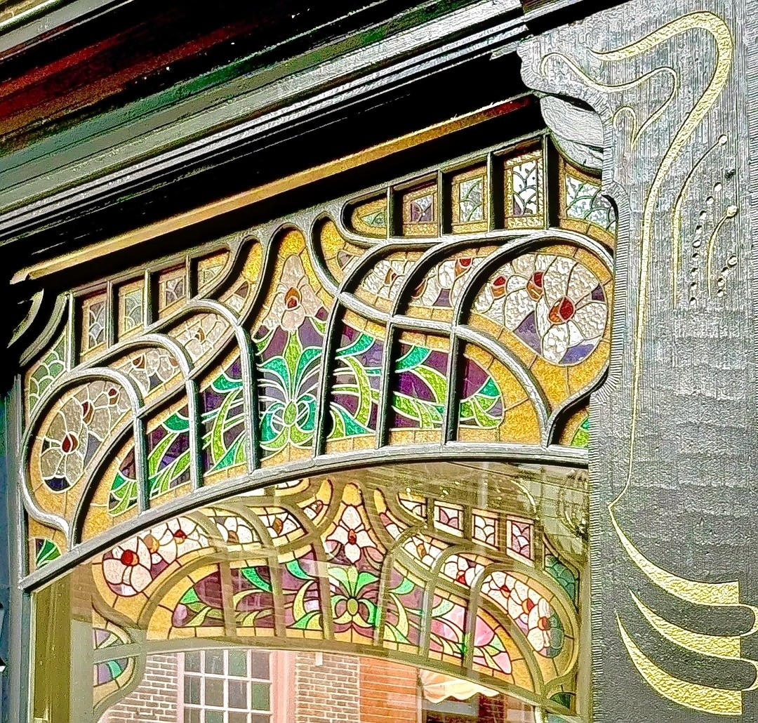Decorative Art Nouveau stained glass window with curved flowing lines and colorful floral patterns