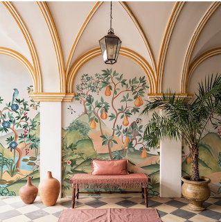 Elegant room with arched ceiling, painted mural, bench, pottery, and potted palm