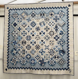 Blue and white patchwork quilt with geometric patterns hanging on wall