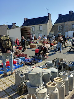 Outdoor antiques market with milk churns and vintage items in a French village square