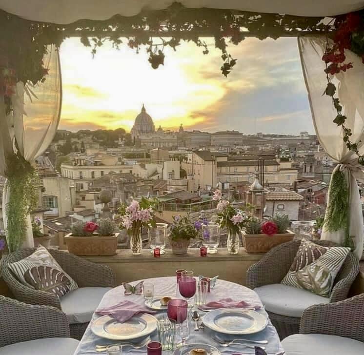 Rooftop dining terrace with sunset view over Rome cityscape and St. Peter's Basilica dome