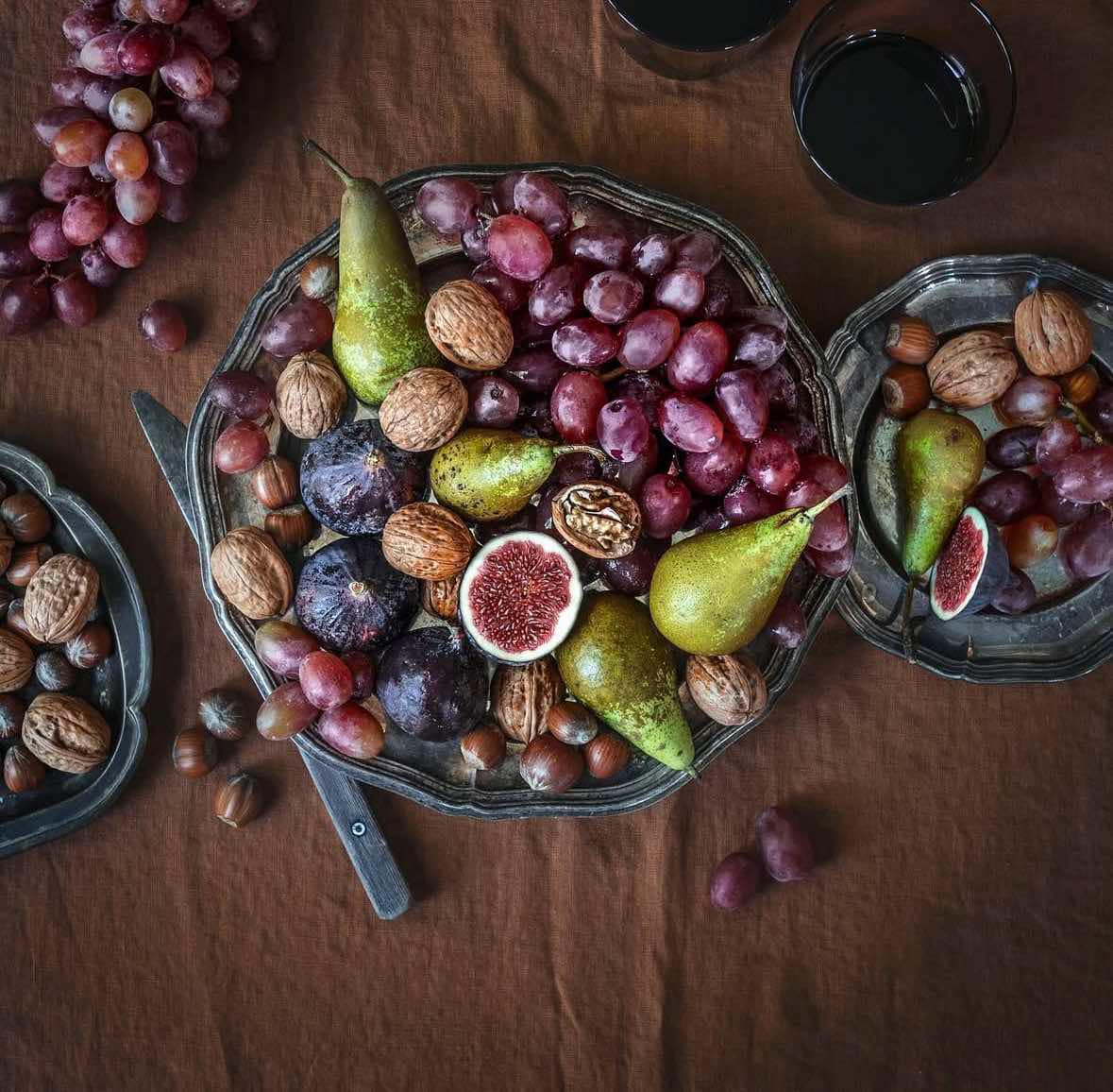 Overhead view of fruit bowl with grapes, pears, figs and walnuts on wooden table