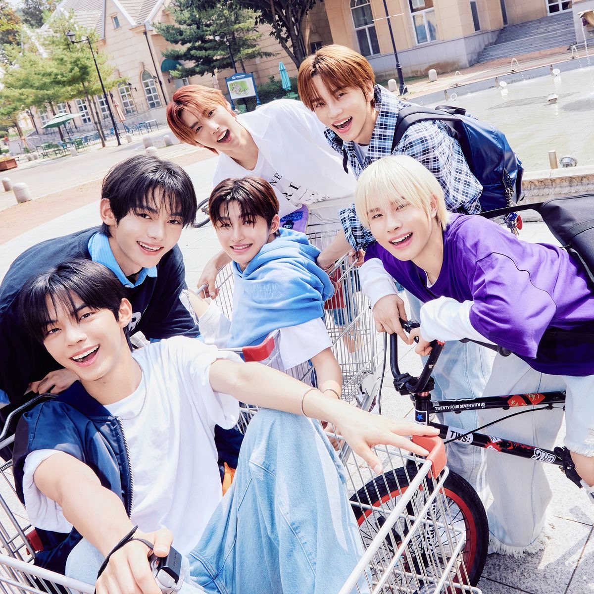 Six young men in colorful clothing posing together outdoors with a shopping cart